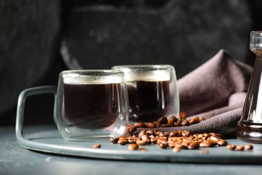 Cam bardaklar dolusu lezzetli kahve ve koyu arkaplanda fasulye kompozisyonu.