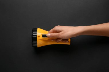 Koyu arkaplanda modern el feneri olan bir kadın.