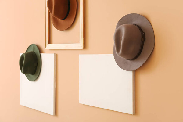 Стильные шляпы и пустые плакаты, висящие на цветной стене