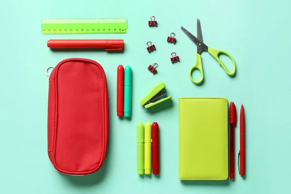 Pencil case with stationery on color background