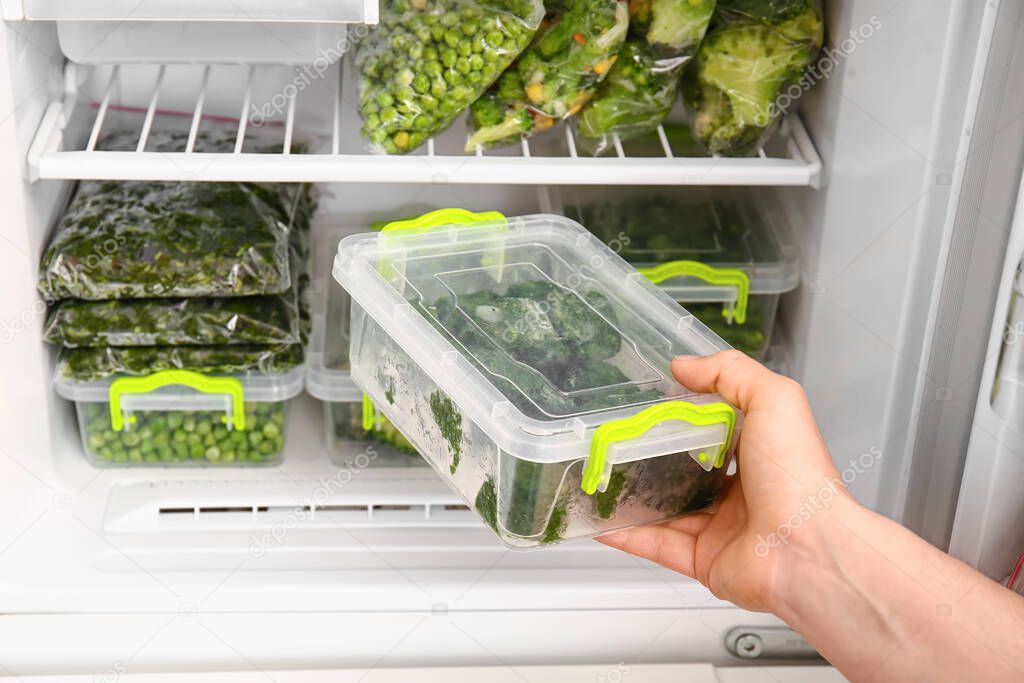 Woman putting container with vegetables in refrigerator