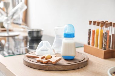 Mutfaktaki çıngıraklı bebek için bir şişe süt.