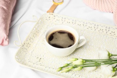 Bir fincan kahve ve çiçeklerle dolu bir tepsi.