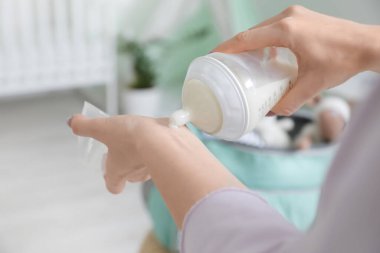 Bebek mamasının sıcaklığını kontrol eden kadın, yakın plan.