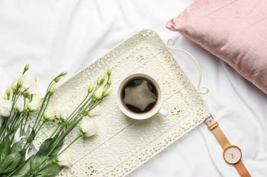 Bir fincan kahve ve çiçeklerle dolu bir tepsi.