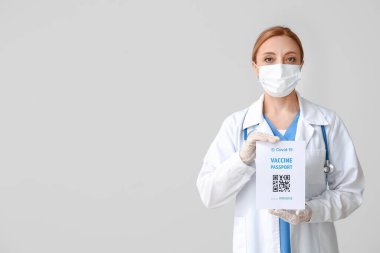 Gri arka planda bağışıklık pasaportu olan doktor.