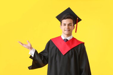 Erkek mezun öğrenci renk arkaplanında bir şey gösteriyor