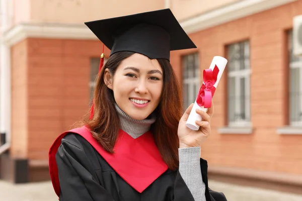 Female student in bachelor robe and with diploma on her graduation day
