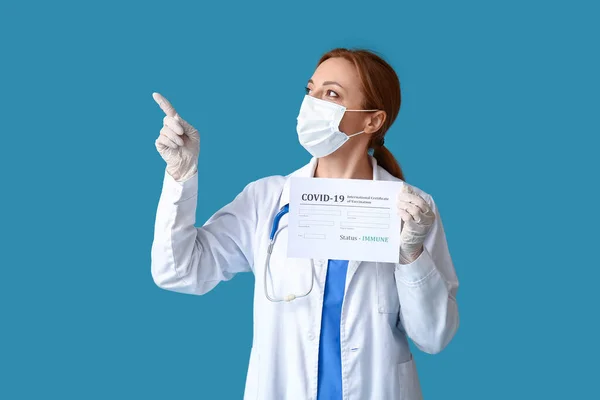 Doctor with blank form of International Certificate of Vaccination showing something on color background