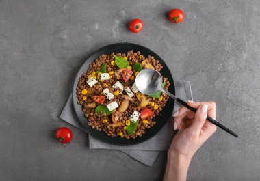 Sebzeli ve peynirli lezzetli mercimek yiyen bir kadın.