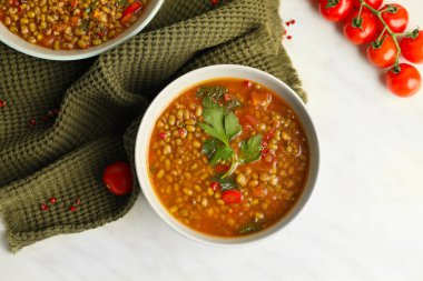 Beyaz arka planda bir kase lezzetli mercimek çorbası.