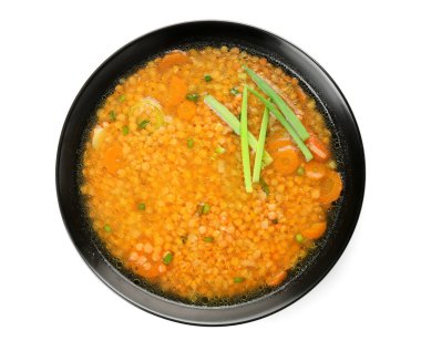 Beyaz arka planda bir kase lezzetli mercimek çorbası.