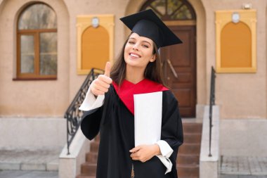 Mezuniyet gününde bornozlu mutlu bayan öğrenci.