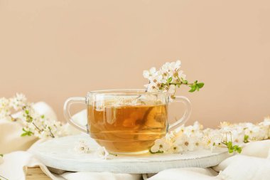 Lezzetli çay ve çiçek açan dallarla dolu bir fincan.