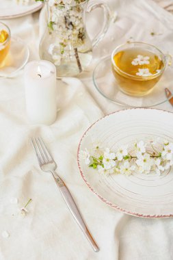 Çiçek açan dalları ve hafif arka planda bir fincan çayı olan masa ayarları