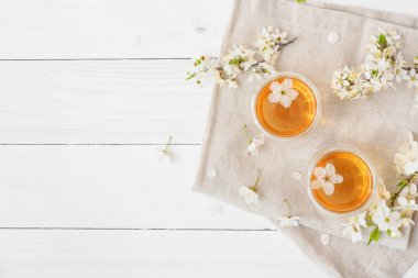 Lezzetli çay bardakları ve hafif ahşap arka planda çiçek açan dallar.