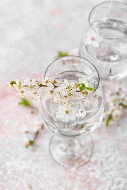 Su dolu bardaklar ve arkaplanda çiçek açan dallar