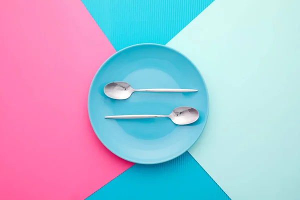 色彩背景上有盘子的干净勺子 — 图库照片