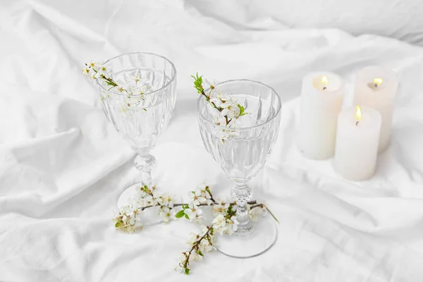 Gläser Mit Wasser Und Blühenden Zweigen Auf Hellem Hintergrund — Stockfoto