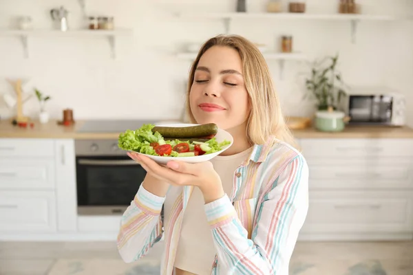 台所でおいしいソーセージと野菜サラダを持つ若い女性 — ストック写真