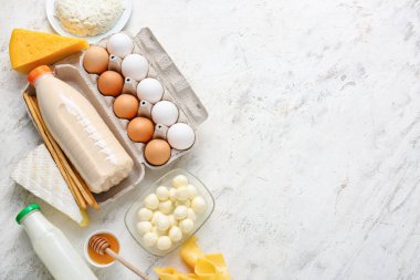 Farklı süt ürünleri, tavuk yumurtaları, bal ve hafif arka planda Grissini.