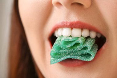 Ağzında şeker olan güzel genç bir kadın, yakın plan.