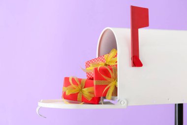 Renk arkaplanında hediyeler olan posta kutusu