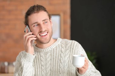 Evde cep telefonuyla konuşan yakışıklı genç adam.