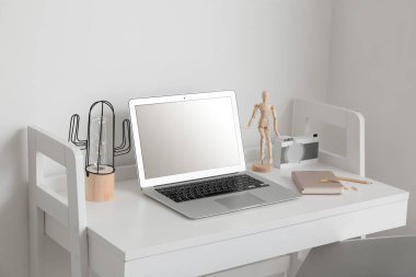 Işık duvarının yanında dizüstü bilgisayarı ve dekorasyonu olan modern bir iş yeri