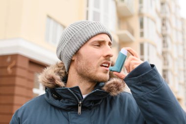 Astımı olan genç bir adam dışarıda astım krizi geçiriyor.