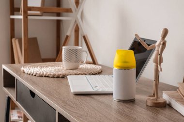 Oda da bir şişe oda spreyi ve laptop var.