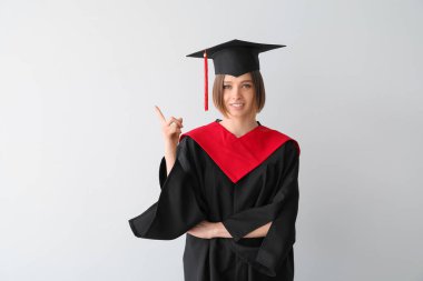 Mezun olan bayan öğrenci arka planda bir şey gösteriyor.