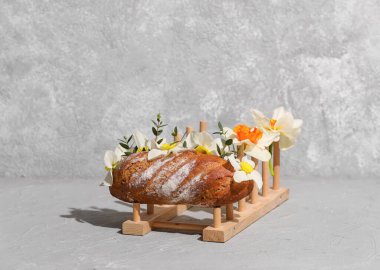 Gri arka planda lezzetli taze ekmek ve çiçeklerle yaratıcı kompozisyon