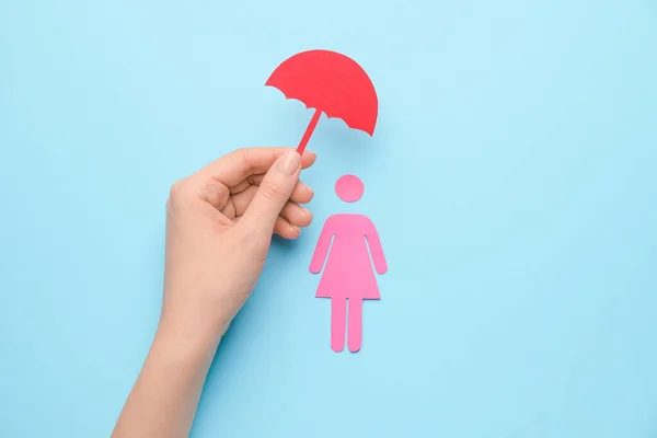 Female hand and human figure with umbrella on color background. Health care insurance concept