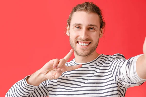 Junger Mann Zeigt Siegesgeste Auf Farbigem Hintergrund — Stockfoto