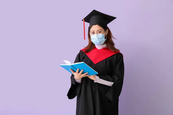 女性卒業生で保護マスクと本の色の背景 — ストック写真