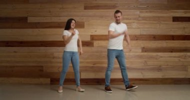 Ahşap duvarın yanında dans eden mutlu genç çift