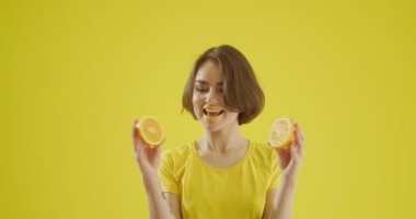Sarı arka planda dilimlenmiş limonu olan şık genç bir kadın.