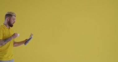 Arka planda gazete ve bir fincan kahveyle gezen genç adam.