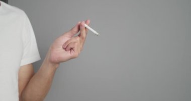 Gri arka planda sigara içen genç adam