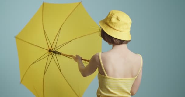 Gri Arka Planda Sarı Şemsiyeli Şık Bir Genç Kadın — Stok video