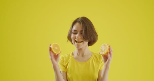 Elegante Mujer Joven Con Limón Cortado Sobre Fondo Amarillo — Vídeo de stock