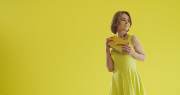 黄色の背景に袋を持つスタイリッシュな若い女性 — ストック動画