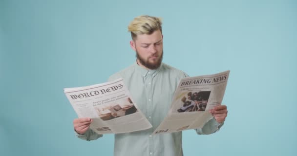 Συναισθηματικός Νεαρός Άνδρας Που Διαβάζει Εφημερίδες Έγχρωμο Φόντο — Αρχείο Βίντεο