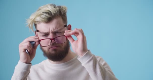 Junger Mann Putzt Seine Brille Auf Farbigem Hintergrund — Stockvideo