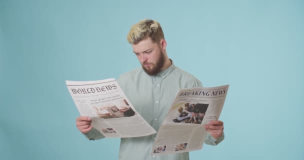 Joven Confundido Leyendo Periódicos Sobre Fondo Color — Vídeos de Stock