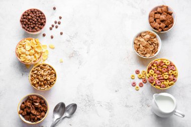 Farklı mısır gevrekleri ve arka planda süt olan kaseler