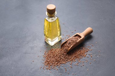 Keten yağlı bir şişe ve koyu arkaplanda tohumlar