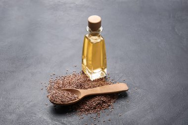 Keten yağlı bir şişe ve koyu arkaplanda tohumlar