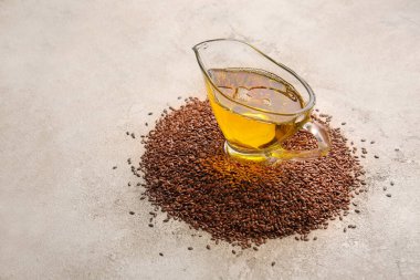 Keten yağlı sos teknesi ve grunge arka planda tohumlar.